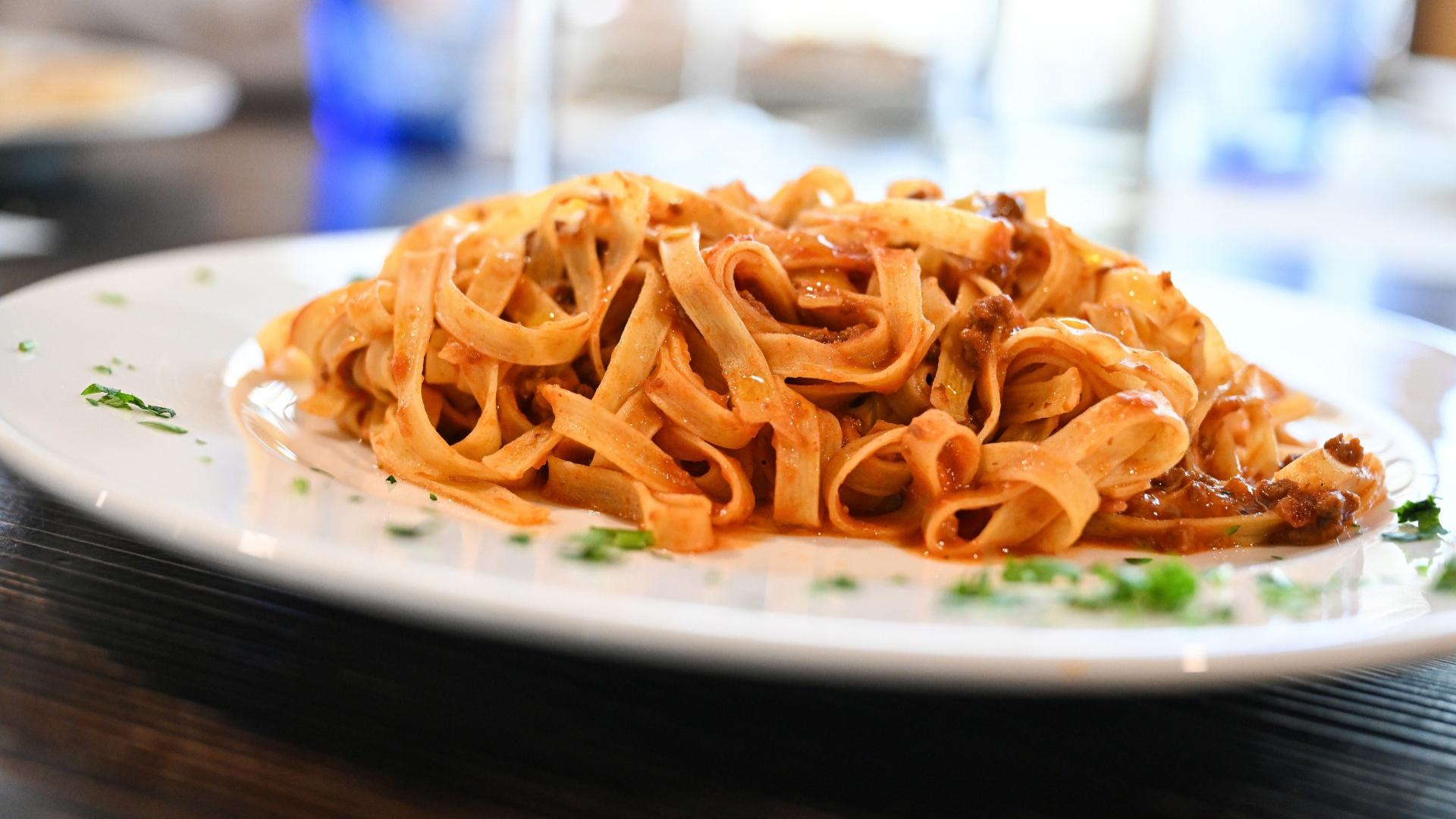 Tagliatelle al sugo di pomodoro e carne, servite su un piatto bianco.