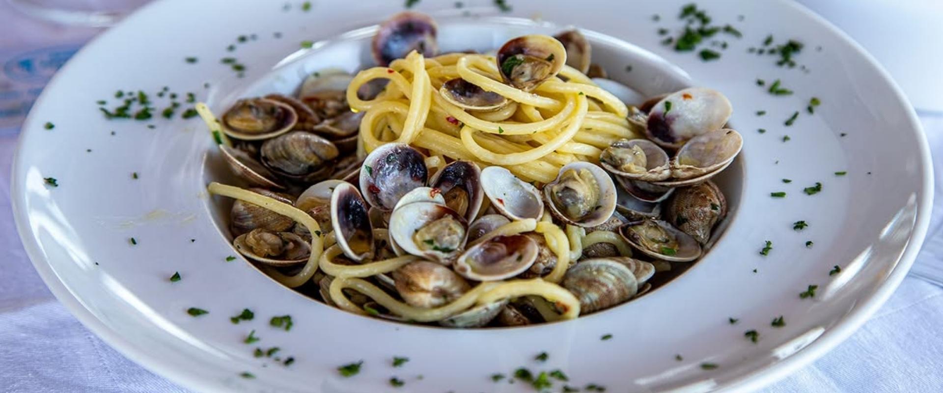 Spaghetti alle vongole con prezzemolo, serviti su piatto bianco elegante.