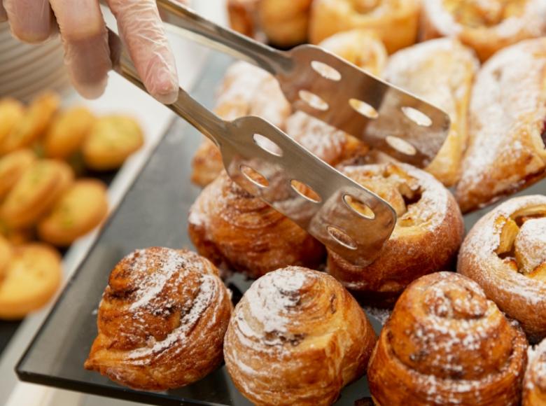 Vassoio di dolci alla cannella con zucchero a velo, serviti con pinze.